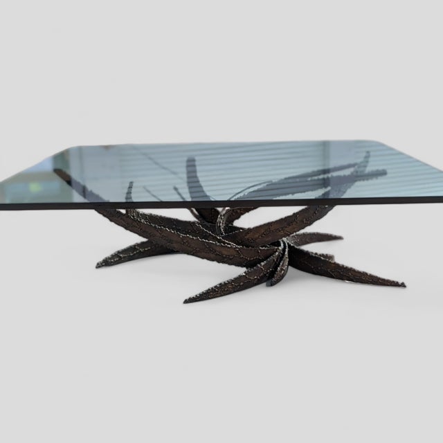 A sculptural cocktail table designed by Silas Seandel in 1972, with a dramatic torch-cut iron base composed as an...