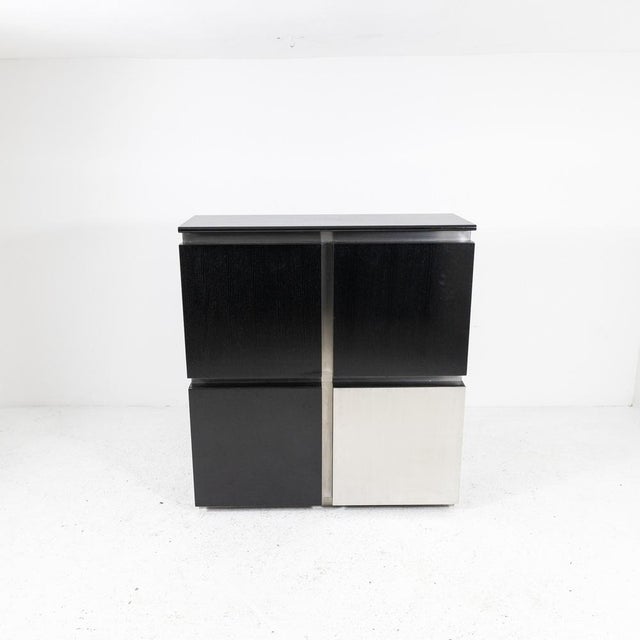 Highboard composed of 4 modules: 2 with black lacquered ash doors, 1 with a steel door, and 1 with a bar cart with a black...