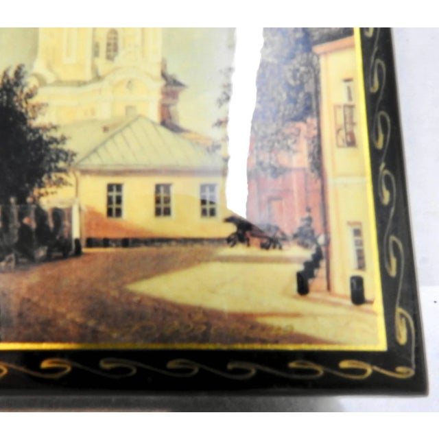 The edges of this black lacquer box from Russia have been decorated with waves of gold. The top boasts scenes of buildings...