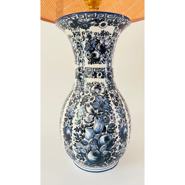 A 20th century table lamp made from a baluster shaped Delfia vase. The white lamp is decorated with lush flowers, leaves...