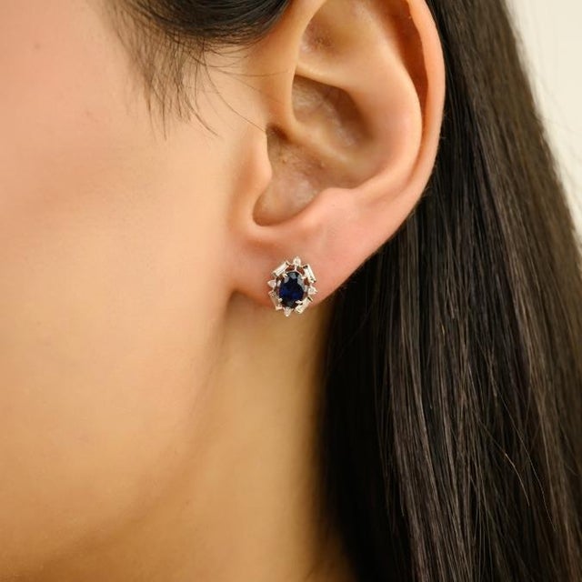 These elegant art deco inspired stud earrings feature two oval cut natural blue sapphires totaling 1.47 carats, set in 14K...