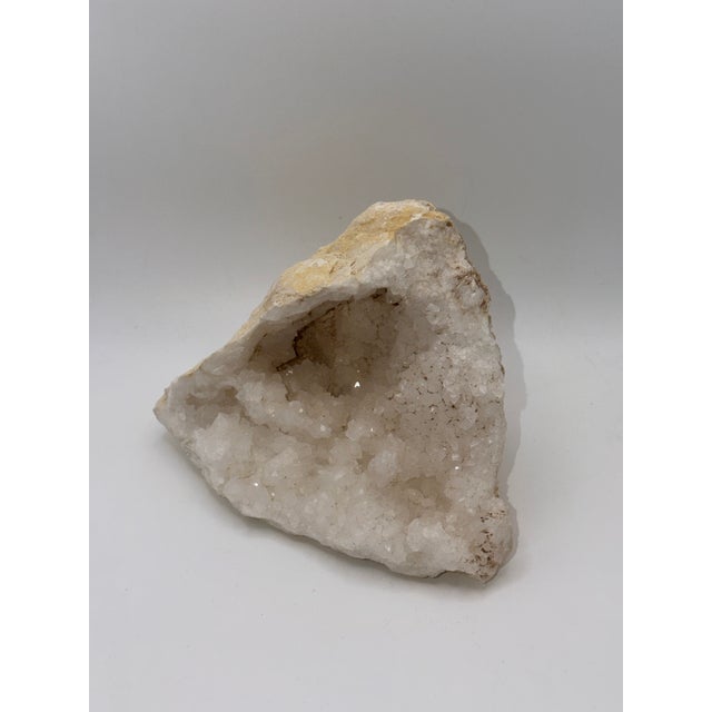 Authentic natural calcite geode featuring a luminous crystalline interior and raw stone exterior. A sculptural mineral...