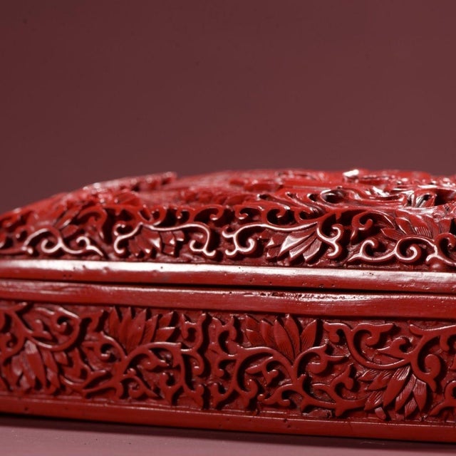 A gorgeous hand-carved cinnabar lacquer rectangular box with domed lid. Intricate deep relief carvings depict a...