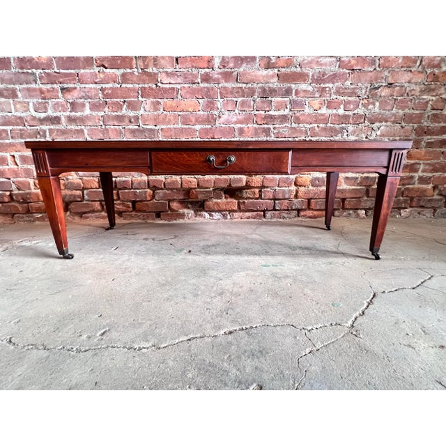 This classic table has one drawer with a small metal pull and fluted details on the legs. It also has casters on the feet.