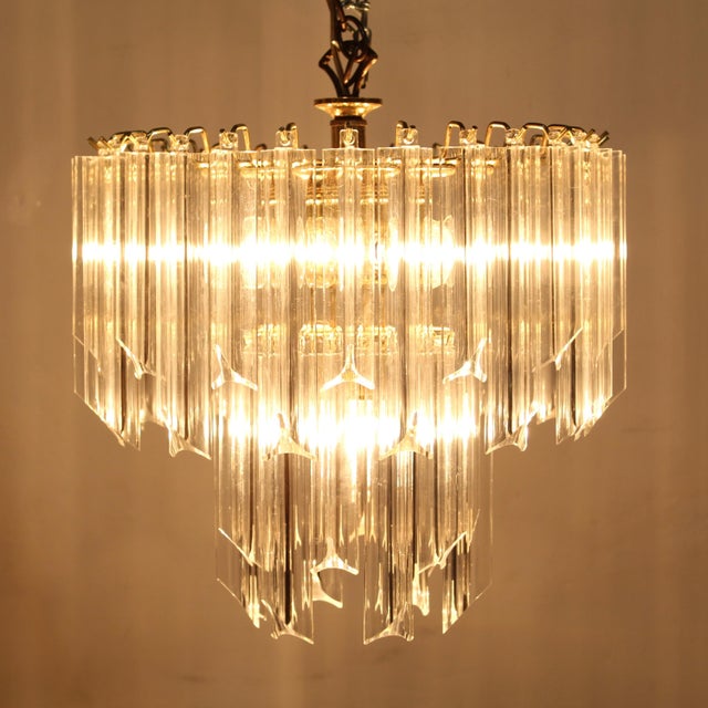 - 40 triangular thick lucite dangles hang from a brass, 2 tiered structure. - 6 chandelier base light sockets - Corded...