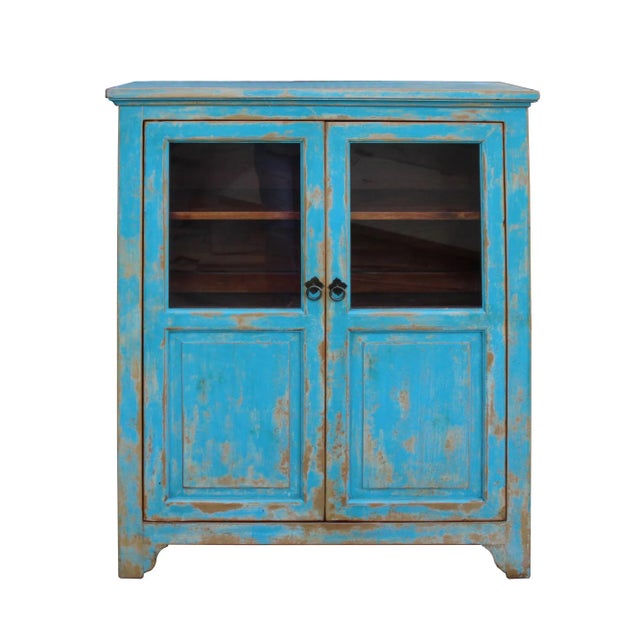 This is a simple distressed bright blue lacquer color display cabinet with two shelves. There is glass on each door....