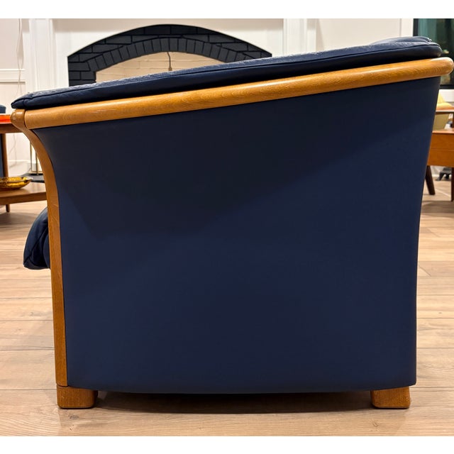 Immaculate Ekornes "Manhattan" leather love seat. Finished in navy blue leather with teak wood trim, both of which are in...