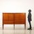 Elegant sideboard with hinged doors, flap and visible drawers. In cherry wood veneer with inlaid thread, brass details and...