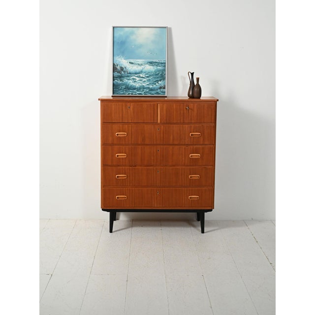 Scandinavian chest of drawers from the 1960s with a double lockable upper drawer, teak frame, and slender black legs....