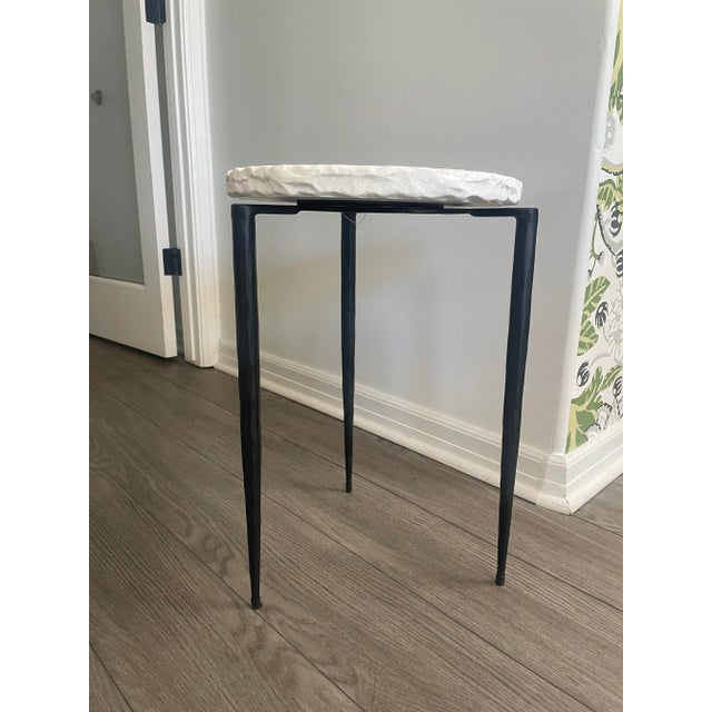 Hand crafted, hand chiseled white marble top set on a cast iron hand forged base featuring tapered legs finished in aged...