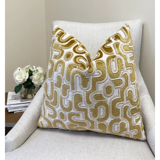 This pillow features bold gold velvet shapes layered over a textured white bouclé background, creating a striking mix of...
