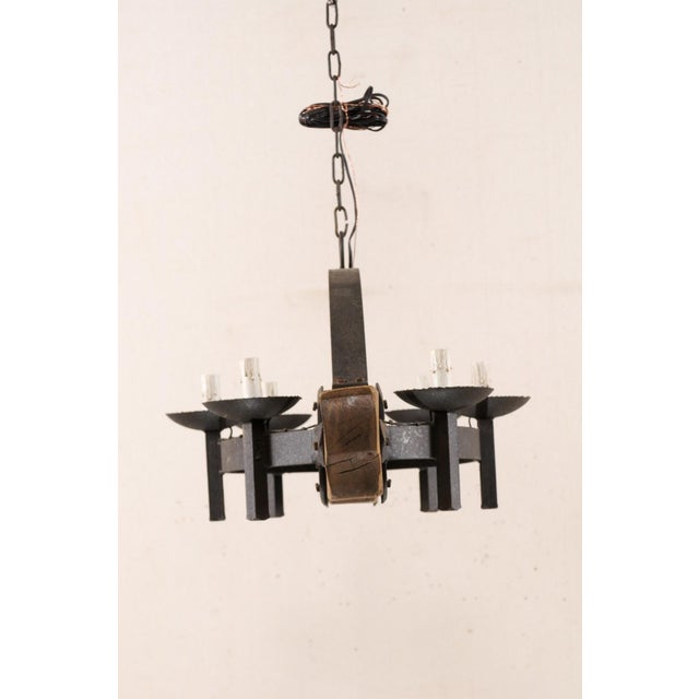 A vintage French six-light wood beam and forged iron chandelier. This mid 20th century chandelier from France features a...