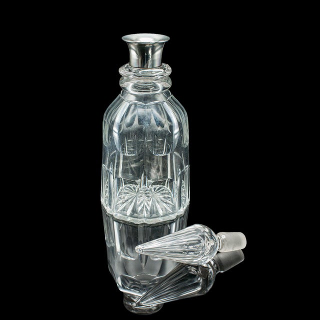 This is a vintage port decanter. An English, cut glass sherry or spirit vessel with a hallmarked silver collar, dating to...