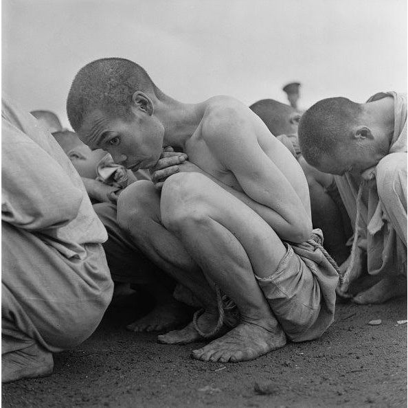 Political Prisoners Premium Rates Apply. A line of South Korean prisoners crouching on the ground, 1950. They are...