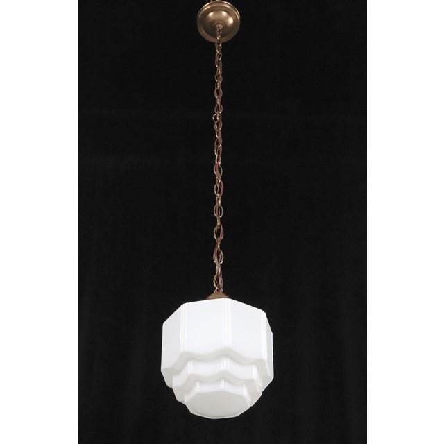 Art Deco hanging pendant light with a milk glass stepped closed shade. Vertical fluting on the shade adds detail and is...