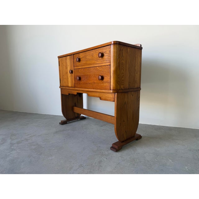 A distinctive 1940s Art Deco solid oak cabinet featuring a warm honey-toned finish and beautiful oak grain throughout....