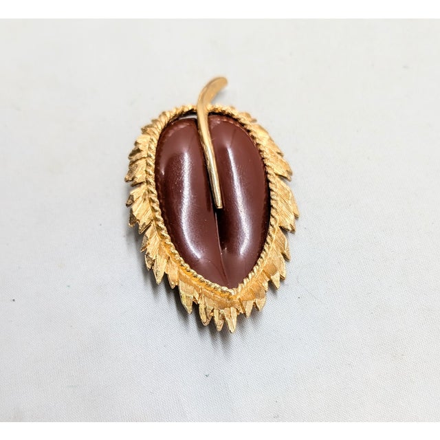 Circa 1966 goldtone and molded red resin leaf brooch with security clasp. Marked "NAPIER©" on the back of the stem....