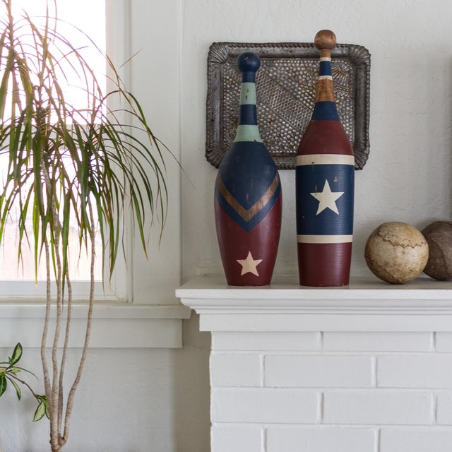 A pair of early 20th-century circus juggling pins or Indian clubs, featuring solid, turned wood painted with red, white,...