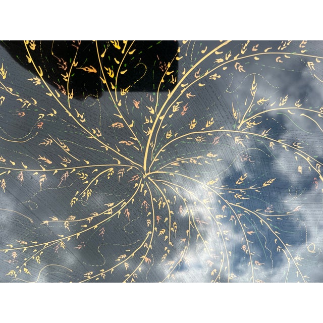 Beautiful black lacquered tables with hand painted gold painted floral motif on top.