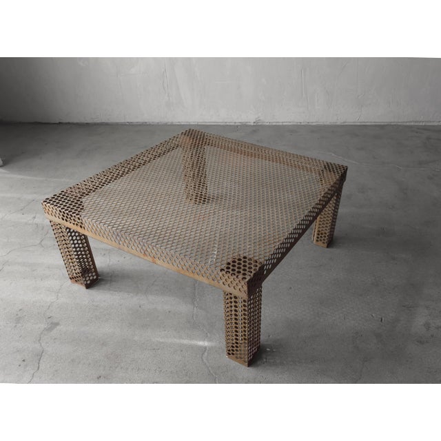 Striking perforated metal coffee table featuring uniform circular cutouts that create a strong geometric presence while...