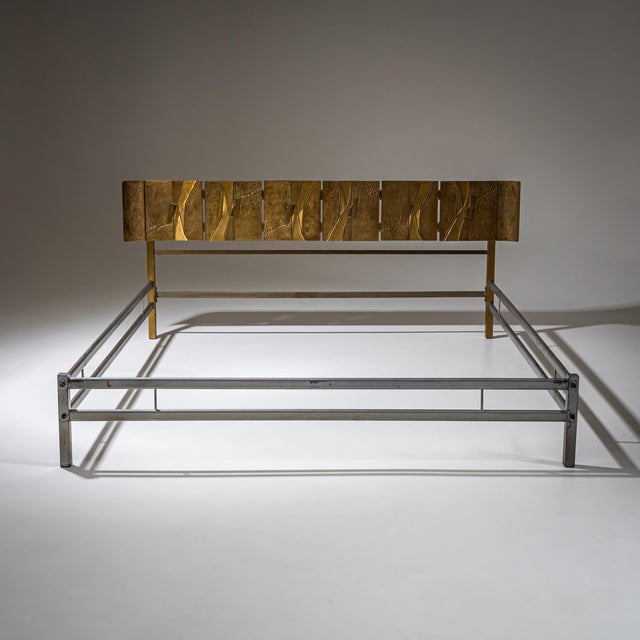 Queen bed with metal frame and brass headboard featuring asymmetrically arranged panels in a Brutalist style.