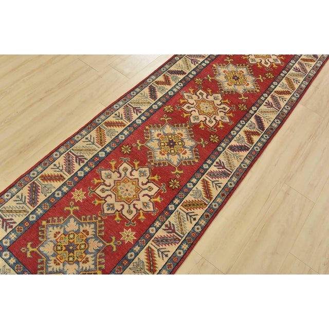 A tribal Caucasian Kazak runner hand-knotted with fine wool on a cotton foundation. This rug has a row of geometric...