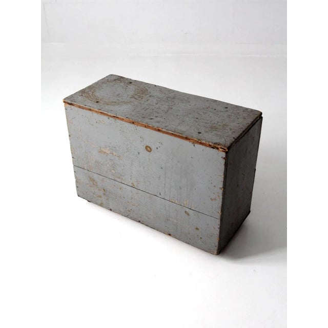 This is a vintage industrial wooden storage box. The wooden box sits on metal casters for easy carting. Aged, gray paint...