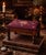 A charming vintage French Provincial footstool featuring hand-worked burgundy wool needlepoint upholstery with a delicate...