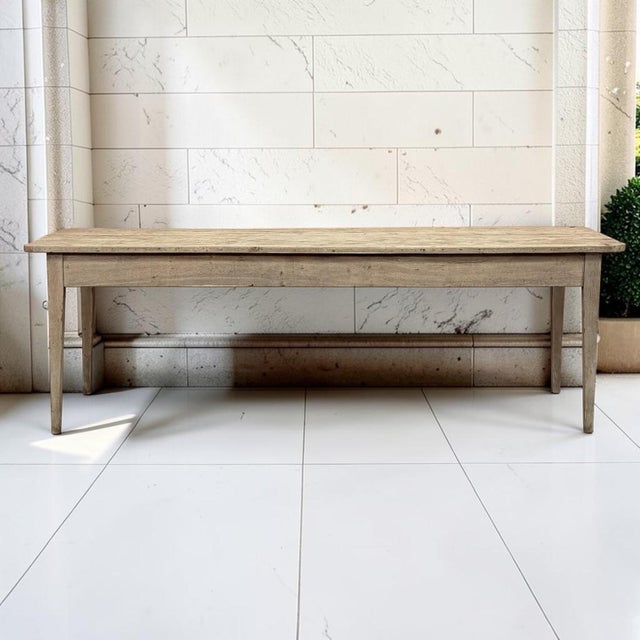 A late 18th century French farm table with a long plank top, a deep apron, and square legs tapering to the floor in the...