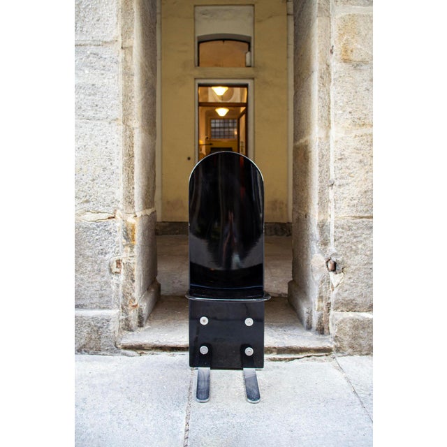 Twelve black lacquered wooden chairs with chromed steel legs and exposed screws and washers for fastening. Pelicano model...