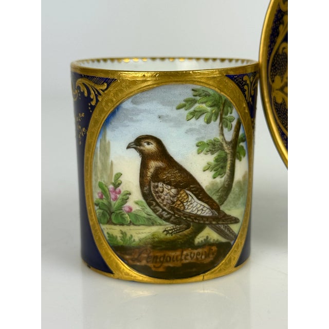 19th Century French Sevres Porcelain Hand Painted Cup & Saucer The cup is a small, cylindrical vessel with a deep cobalt...