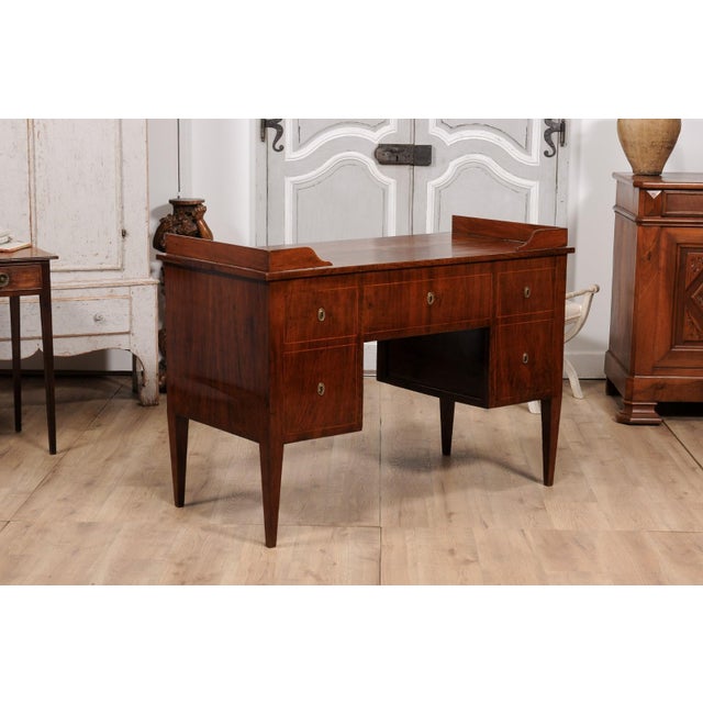 An Italian walnut and mahogany desk from circa 1820 with dark brown leather pull-out drawer, five drawers and thin banding...
