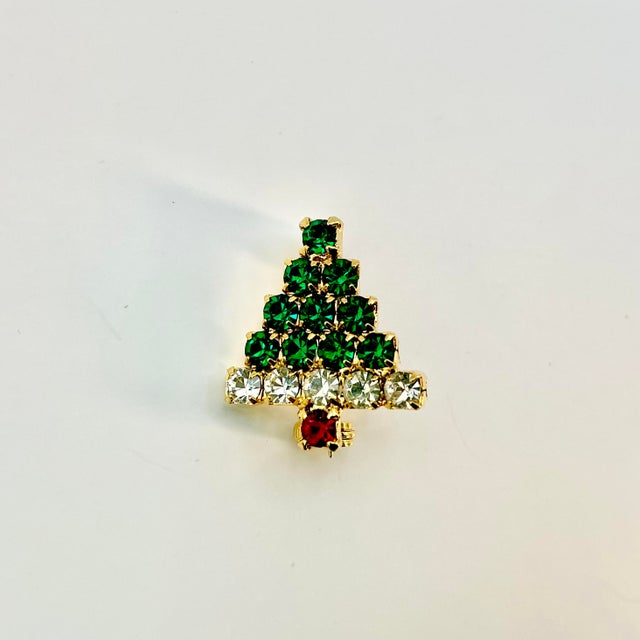 A lovely petite rhinestone Christmas Tree Brooch from the 1980s. It features stacks of dark green rhinestones encased in a...