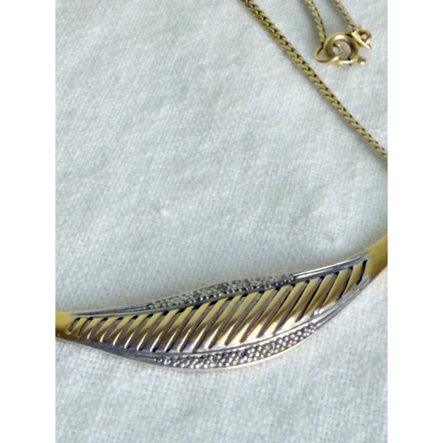 Vintage necklace featuring a sculptural design in a gold-tone finish over a sterling silver base. The piece presents a...