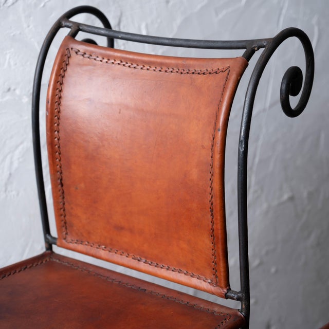 A set of three spanish hacienda wrought iron and leather barstools, 1960s. 17 inches wide by 23 ½ inches deep by 45 inches...