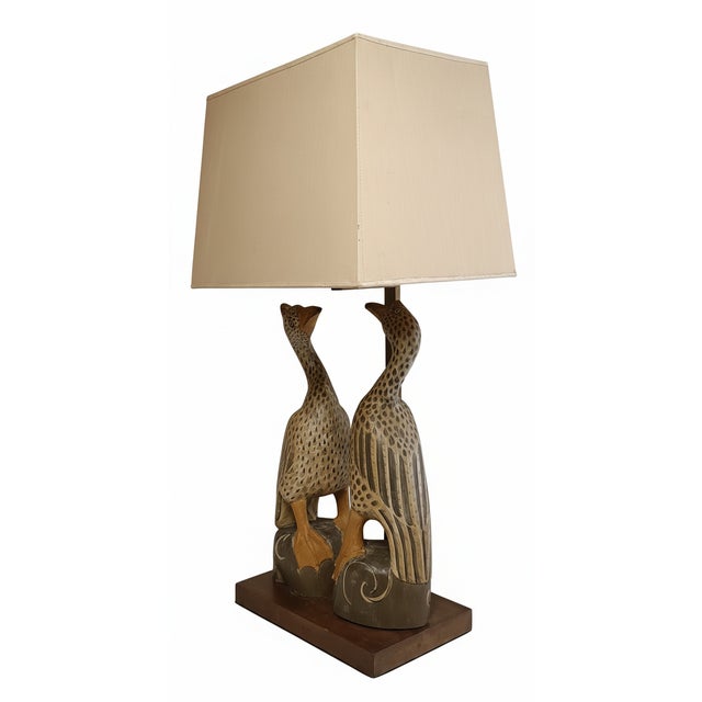 Table lamp depicting a pair of exotic birds in polychrome wood resting on a wooden base. Brass frame and original fabric...