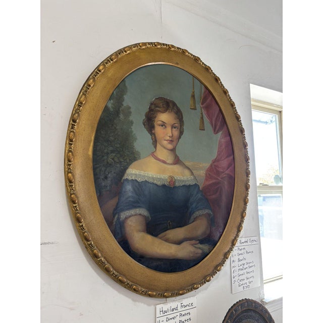 19th century oil portrait of a woman in an off-the-shoulder blue gown trimmed with lace, wearing a coral bead necklace,...