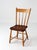 An antique American plank seat chair with a shaped solid wood seat, turned legs, and a spindle back, finished in...