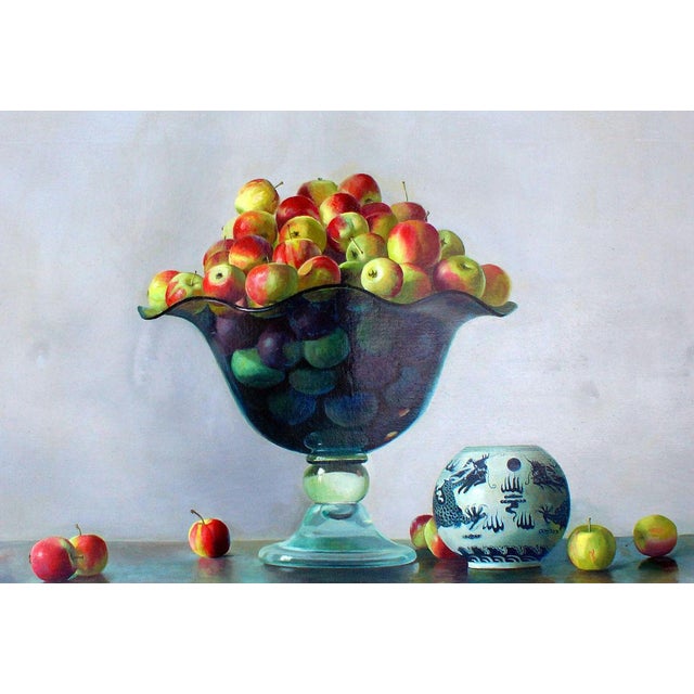 Multicolored apples fill an elegant crystal vase collocated on a smooth surface. This vase is the heart of the composition...