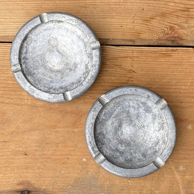 Pair of mid century solid aluminum ashtrays with lettering around the outer edge reading "Cone Automatic Machine Company...
