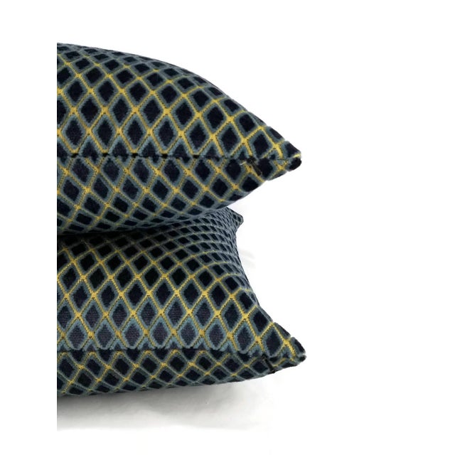 A deep royal blue or others call navy diamond pattern velvet pillow cover. In between the diamond lines are a goldish...