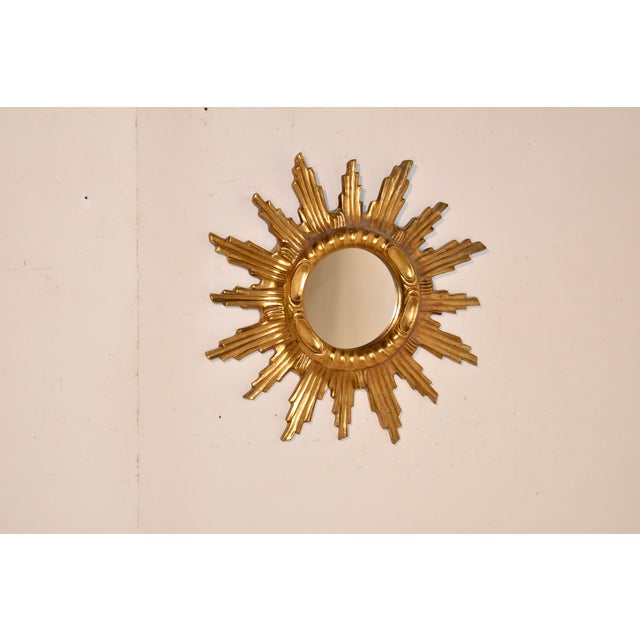 Mid-20th century gilt wood sunburst mirror from France. The central mirror is surrounded by a hand carved edge and outer...