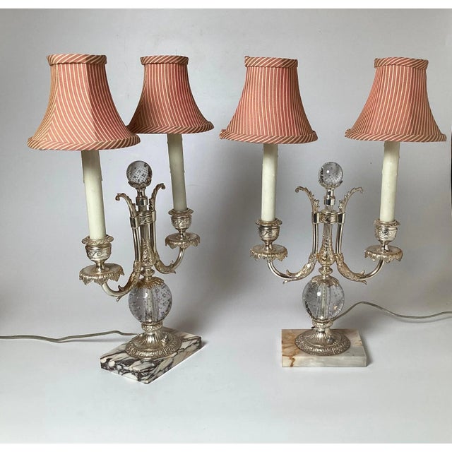An elegant pair of silvered bronze and glass candelabra lamps by Pairpoint . The two light lamps with silvered bronze...