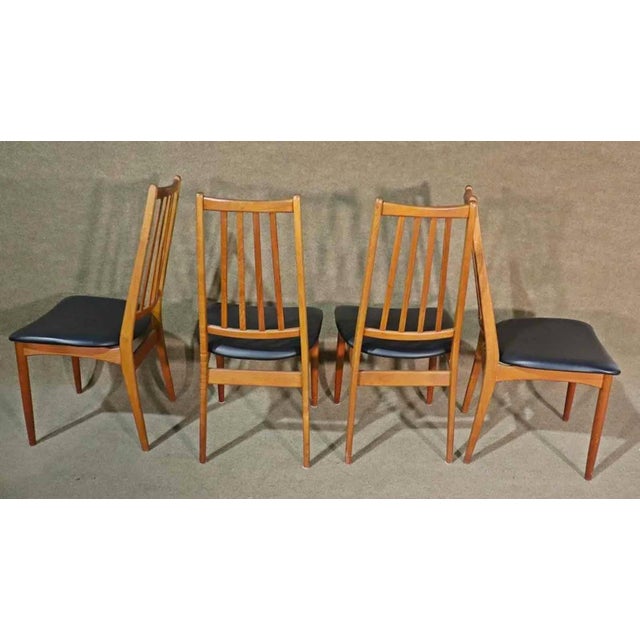 Mid-Century Modern dining chairs from Denmark. Teak wood frames with slat backs and floating vinyl seats.
