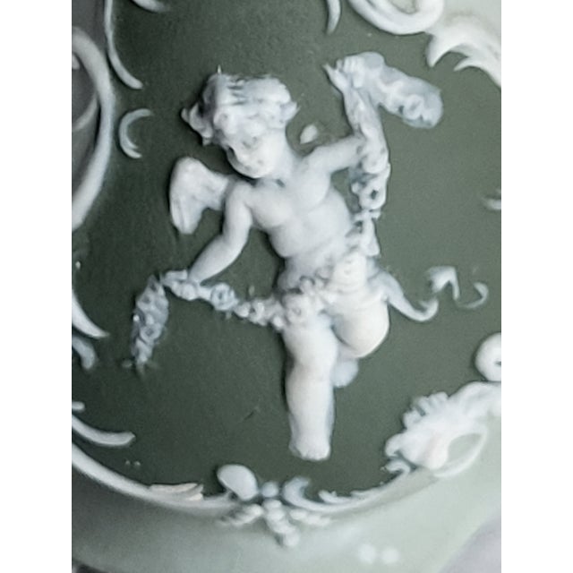 This is a matte green and white bisque porcelain with a raised cherub and ornate side handles. Jasperware is a type of...