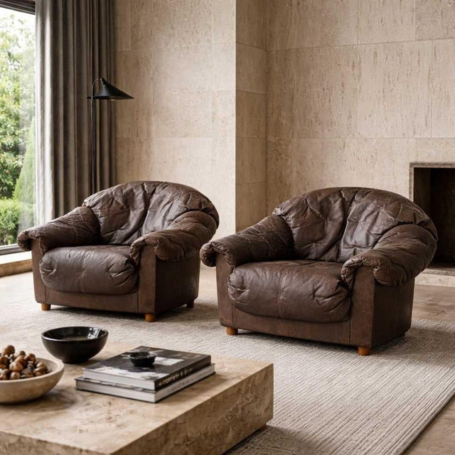 A pair of exceptionally comfortable late 20th-century lounge chairs featuring a relaxed, "slouchy" silhouette. Upholstered...