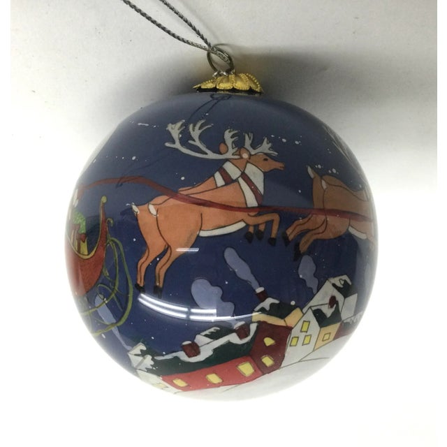 Pretty and colorful Holiday hanging ornament with Santa and his reindeer flying across the globe. In wonderful vintage...