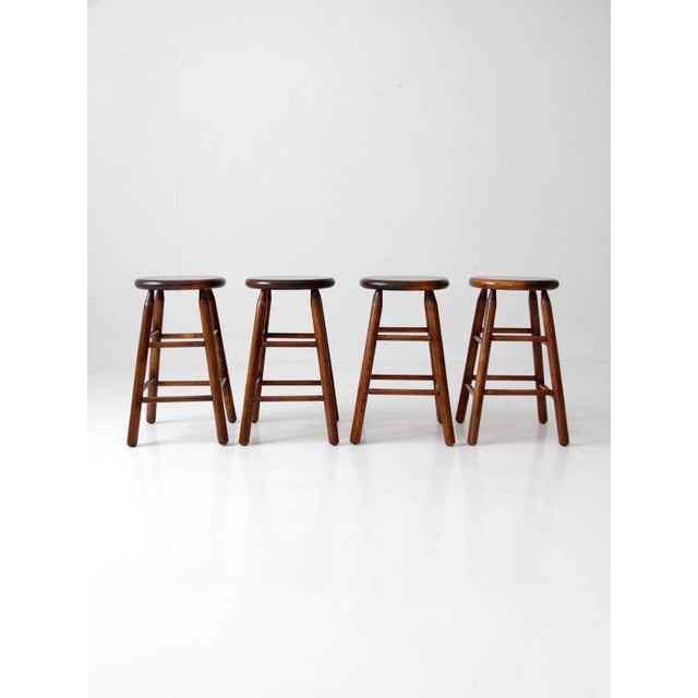 A set of four vintage wood stools in a rich, warm tone, defined by a clean, balanced silhouette that settles effortlessly...