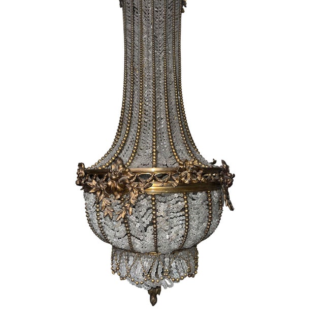 An exquisite late 19th century French chandelier crafted in fine bronze and adorned with cascading beadwork. This elegant...