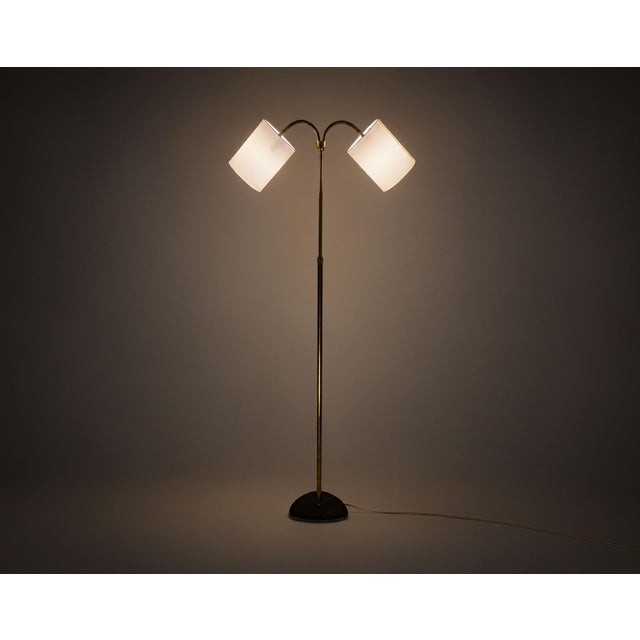 An understated mid-century floor lamp with a heavy plectrum-shaped base of cast iron with its original wrinkly paint, a...